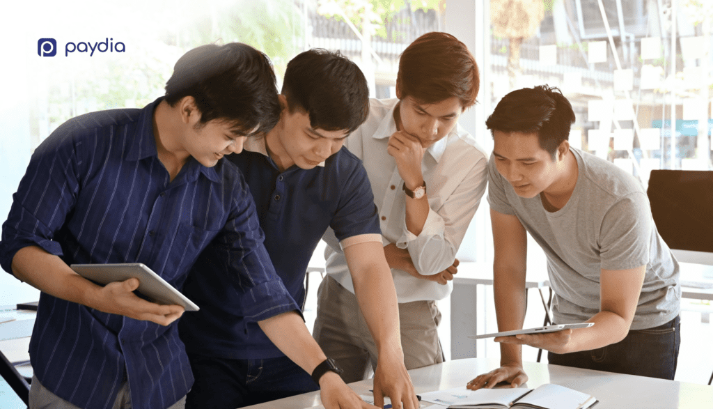 Empat Laki-Laki Asia Diskusi Memberi Saran Proposal Bisnis (Paydia)